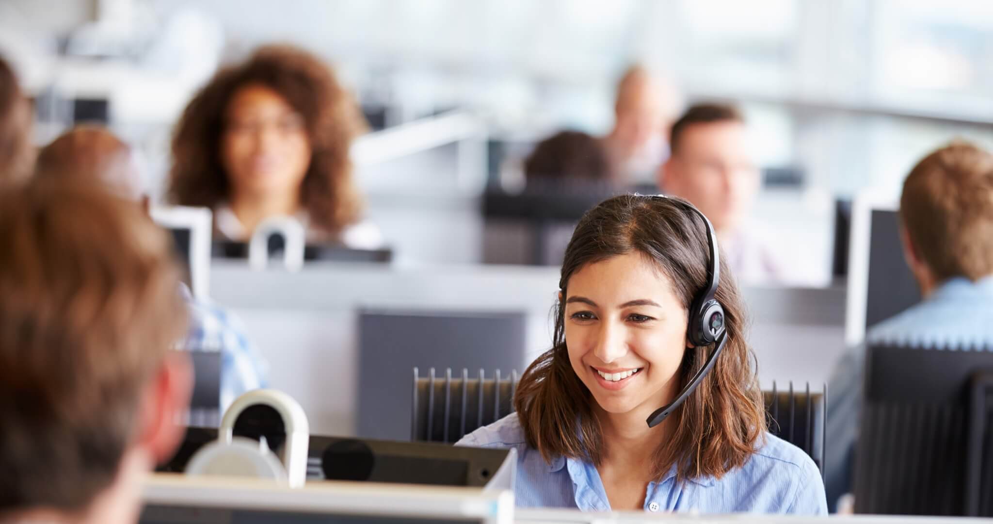 Young woman working in call centre, surrounded by colleagues Call Center